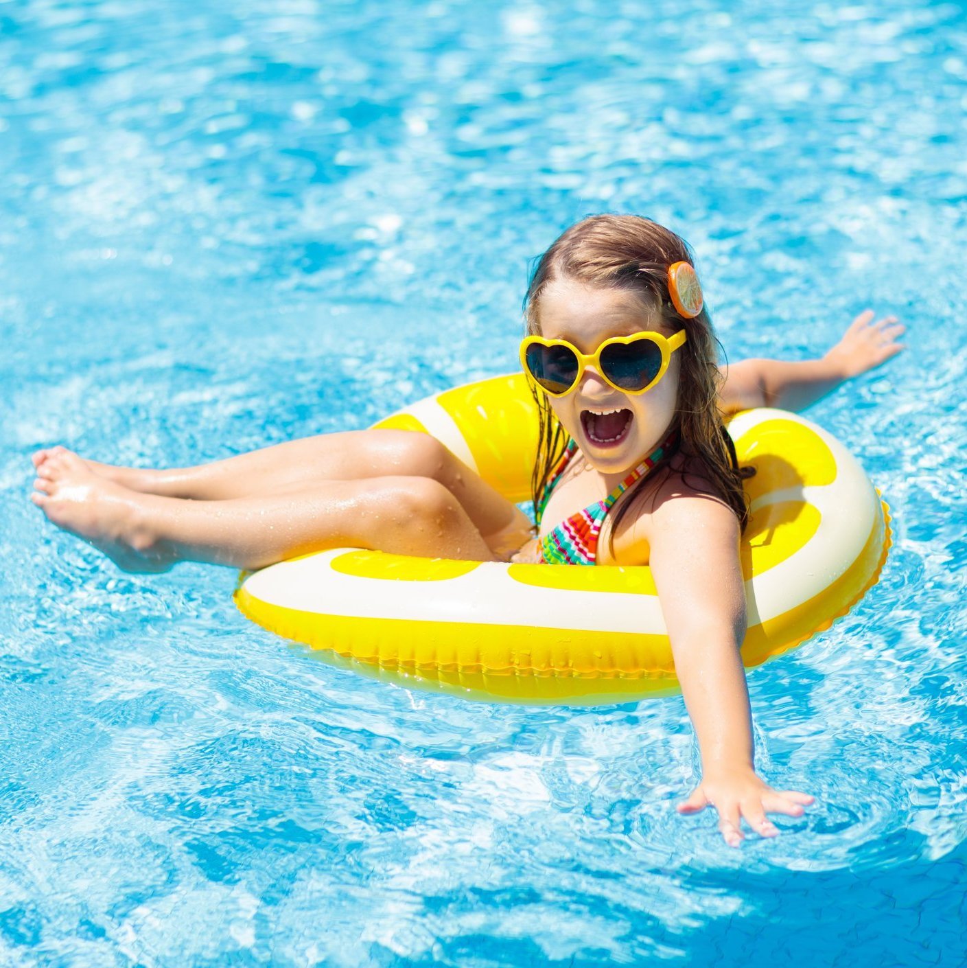 Child in swimming pool on ring toy. Kids swim.